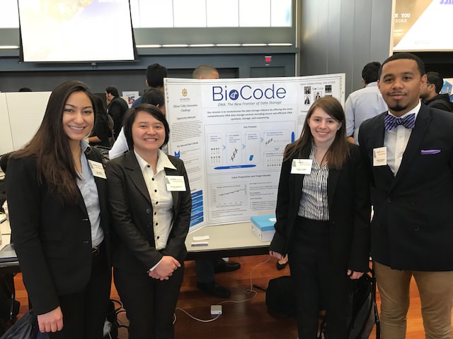 a group of students and faculty in front of a poster presentation