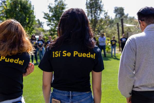 Photo of group gathering, with the focus on the back of a t-shirt that says "si se puede"