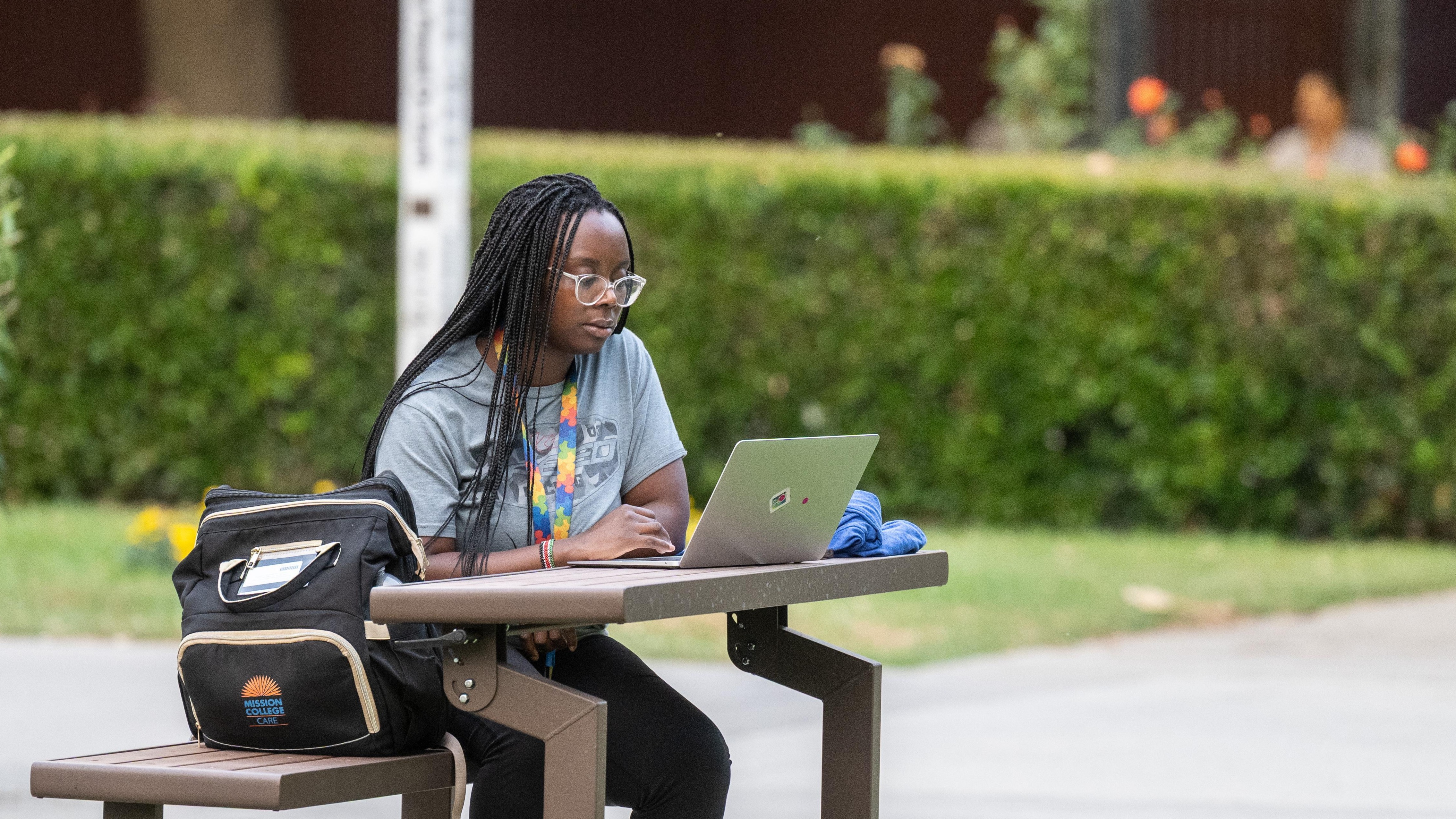 Girl sitting outside on a bench looking at her laptop